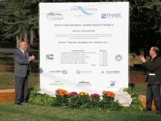 Dignitaries applauding next to the project sign