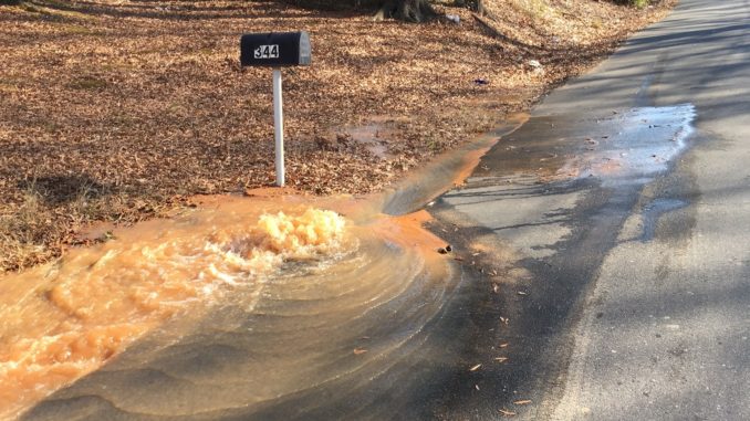 Water bubbling up onto street from leaking main