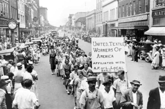 Protesters carrying a sign that says United Textile Workers of America, marching down Main Avenue 1929