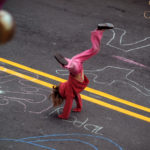 Girl doing handstand in street with sidewalk-chalk drawings around her