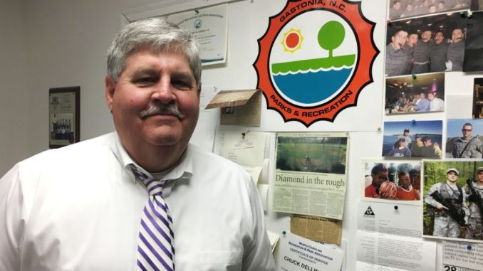 Chuck Dellinger next to Parks and Recreation bulletin board