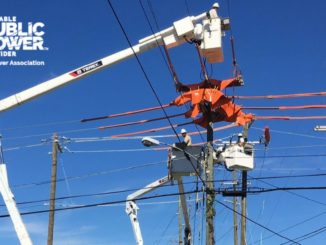 Linemen working way above ground on electric lines. RP3 logo on side.