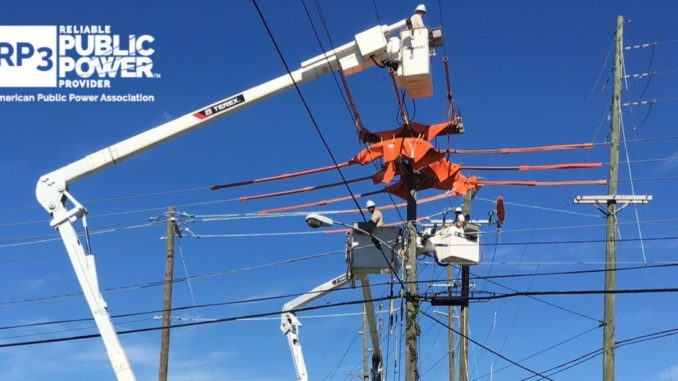 Linemen working way above ground on electric lines. RP3 logo on side.