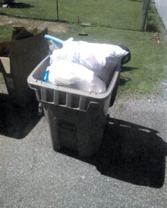 Recycling bin stuffed with bagged trash