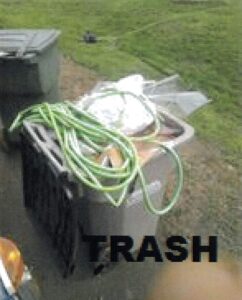 Recycling bin filled with trash and garden hose