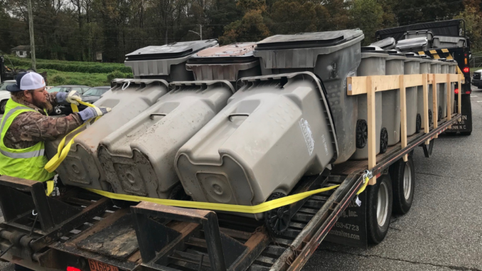 City employee securing recycling carts loaded on a big truck