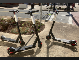 Three black, red and white scooters on the sidewalk