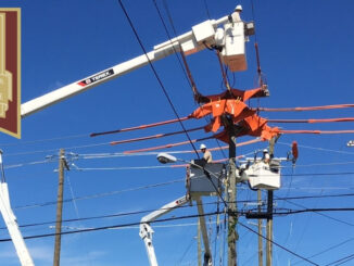 Three line workers in bucket trucks working on electric lines