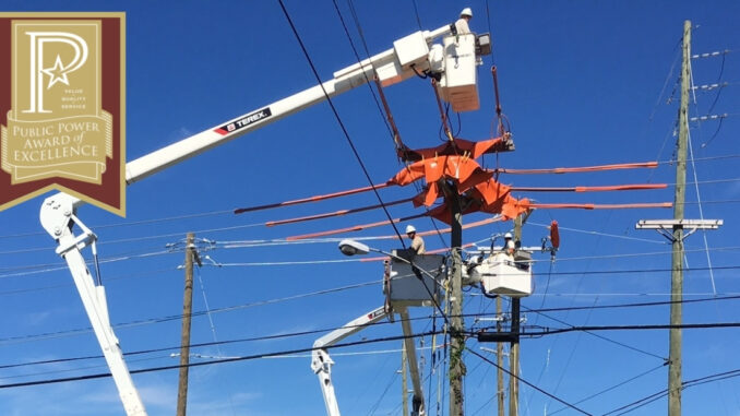 Three line workers in bucket trucks working on electric lines