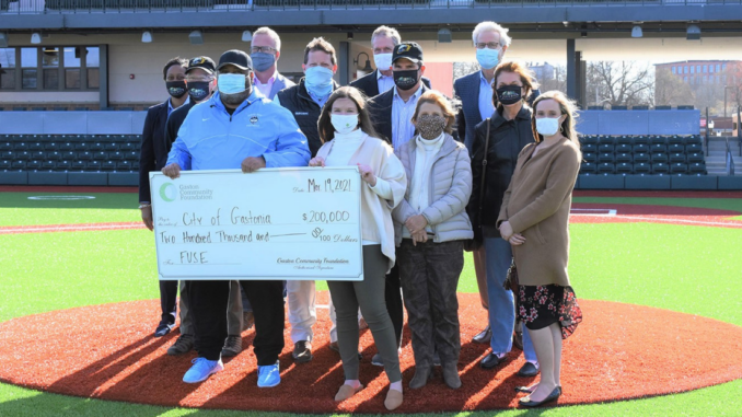 12 people standing at home plate with large ceremonial check