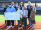 12 people standing at home plate with large ceremonial check