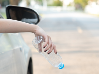 Woman about to drop empty bottle from car window
