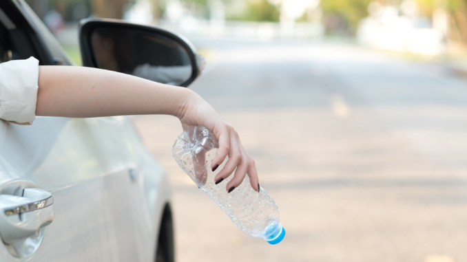 Woman about to drop empty bottle from car window