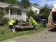 Three employees lift a discarded couch at the curb