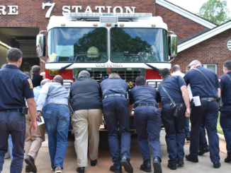 Fire and City officials pushing a firetruck into a fire station