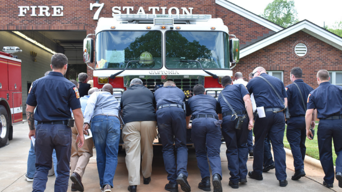 Fire and City officials pushing a firetruck into a fire station