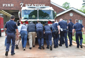 People pushing firetruck into station as part of ceremony