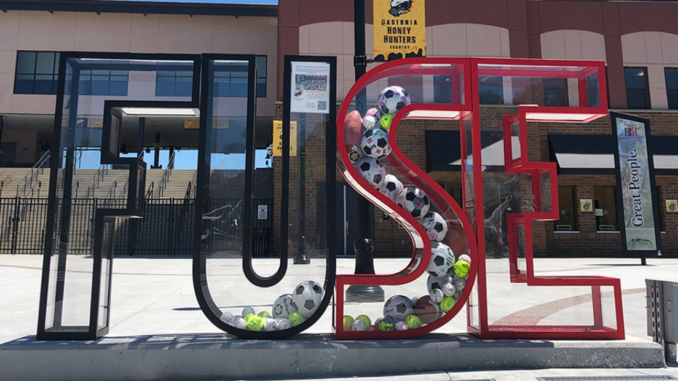 Clear plexiglass FUSE letters at ballpark filled with sports balls