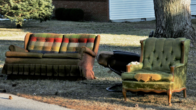 Couch and chair with tattered upholstery along street curb