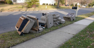 Parts of a sofa and chairs in grass next to a street