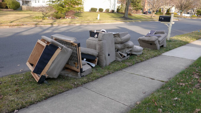 Parts of a sofa and chairs in grass next to a street