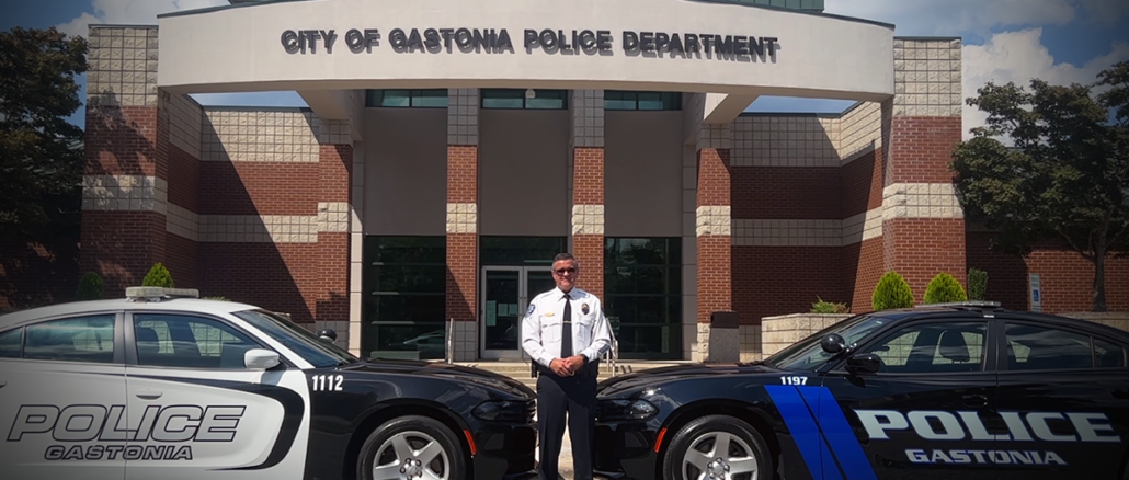 GPD Chief Brittain outside police headquarters with an old police cruiser and a new model of police car