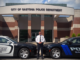 GPD Chief Brittain outside police headquarters with an old police cruiser and a new model of police car